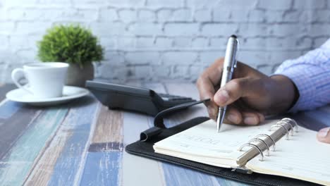 person writing in a planner at a desk