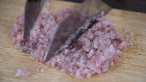 mincing fish filet with two knifes on wooden chopping board - close up