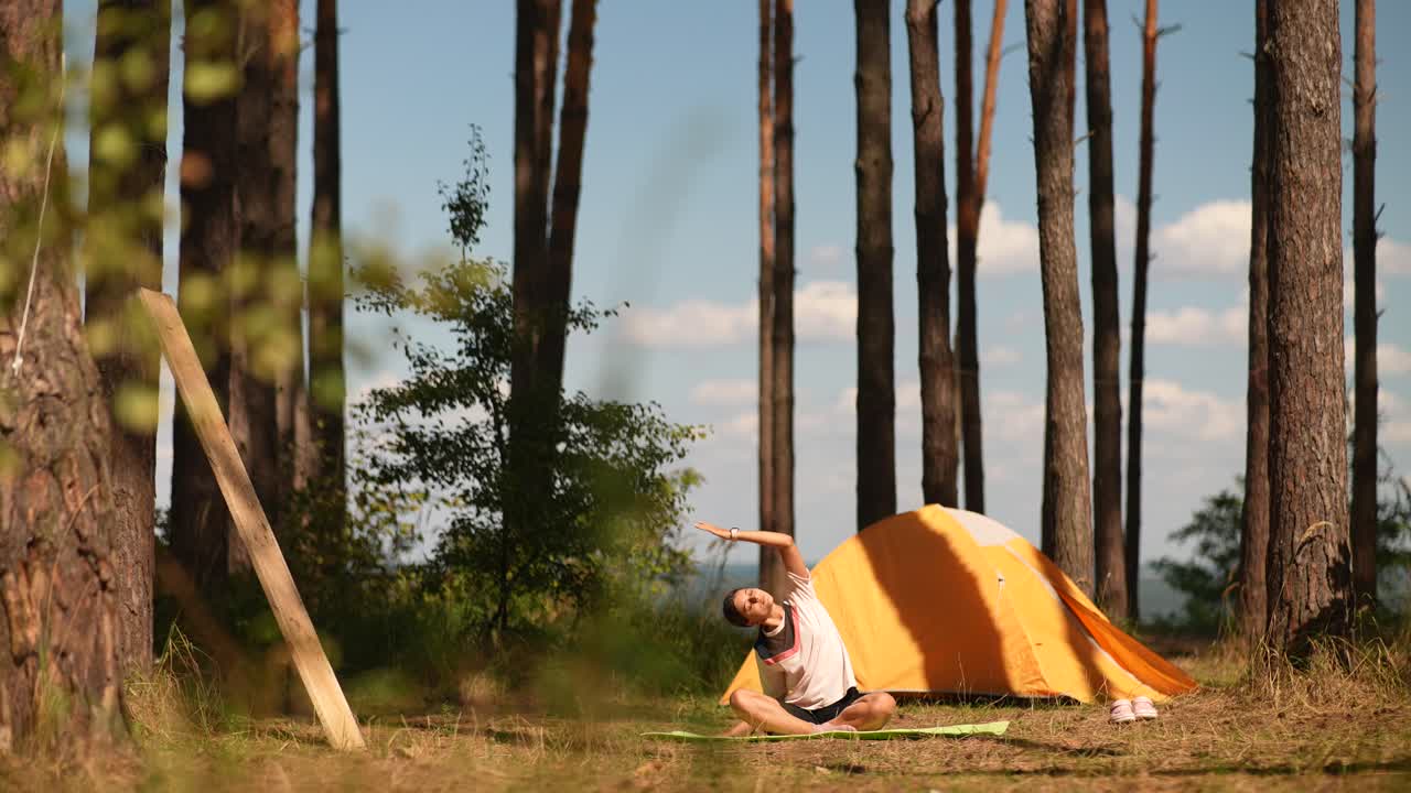 숲 에 있는 캠핑장 에서 요가 를 연습 하는 여자