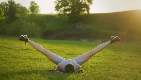 woman doing a workout lying on the grass doing power stretching exercises for her legs