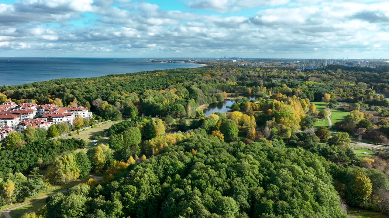 Aerial shot of coastal forest, lakes and nearby residential areas with the Baltic Sea visible along the horizon