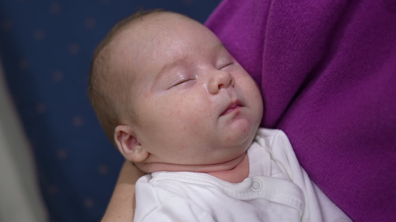 Loving and caring mother is hugging her infant baby son. Mother is rocking her baby while the child sleeping peacefully. Close up.