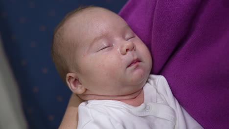 loving and caring mother is hugging her infant baby son. mother is rocking her baby while the child sleeping peacefully. close up.