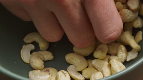 male man hand grabbing cashew nuts in bowl in normal speed to slow motion - healthy food clip 4k