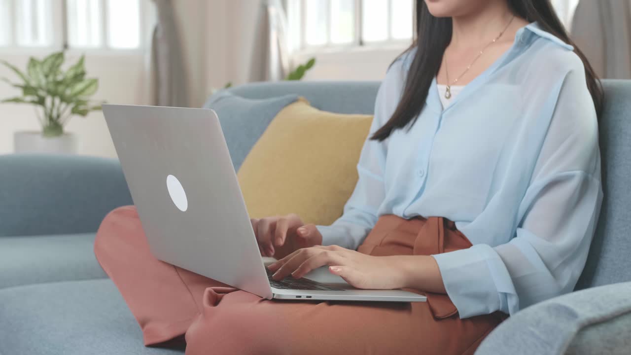 Asian Female Working On Laptop And Smiling At Living Room While Sitting On Sofa, Video In 4K