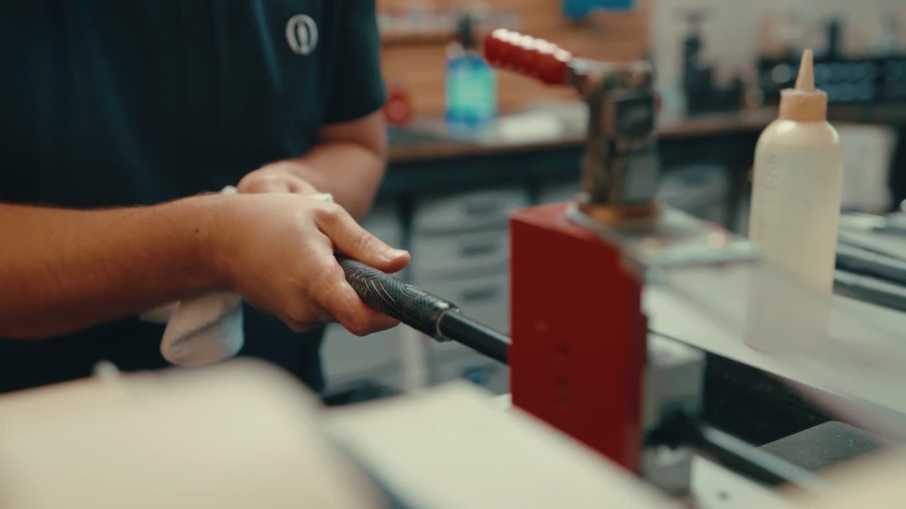 el agarre de vice sostiene el eje del palo de golf como manos masculinas caucásicas se deslizan el agarre del golf sobre el eje del club de golf para el ajuste personalizado en el taller en cámara lenta