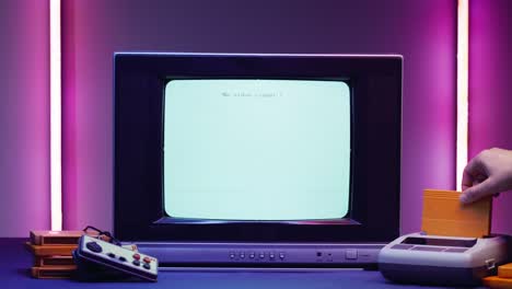 old television with blue screen on purple neon background. close-up of vintage tv and retro playstation, changing cartridges. antique video game, nostalgia