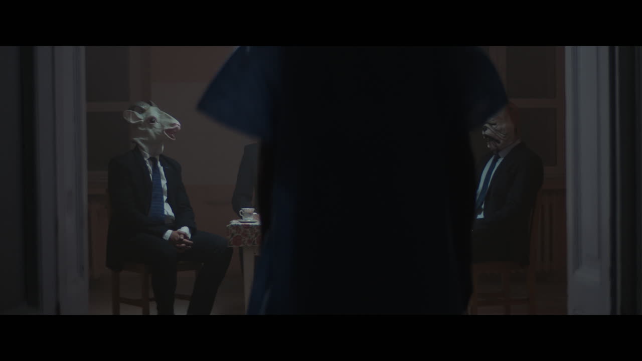 A girl sits at a table with strange figures in animal masks