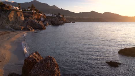 Paisaje-Suave-Y-Tranquilo-En-La-Playa-De-Nerja,-España-Con-Océano-Y-Acantilados-En-La-Distancia