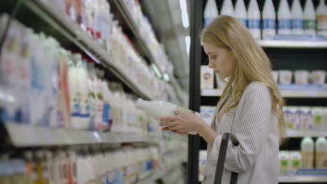 advertise business food health concept - woman in a supermarket standing in front of the freezer and choose buying fresh milk bottle. drink milk for healthy.