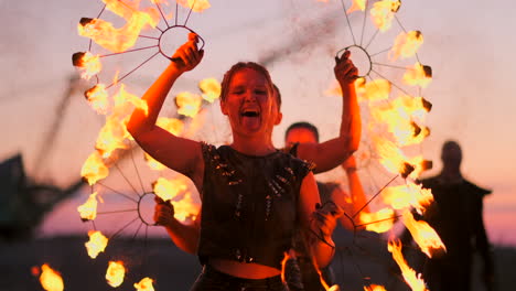 Mujeres-Con-Fuego-Al-Atardecer-En-La-Arena-Bailan-Y-Muestran-Trucos-Contra-El-Hermoso-Cielo-En-Cámara-Lenta