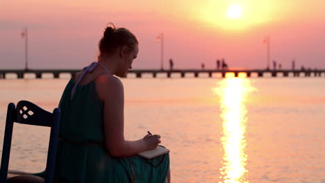 young woman writing in her diary by the seashore