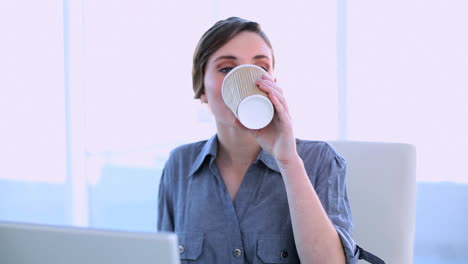 mujer de negocios feliz trabajando en una computadora portátil tomando un café