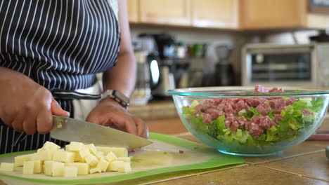 cutting a white, mild cheese into cubes to add to a chopped salad - antipasto salad series