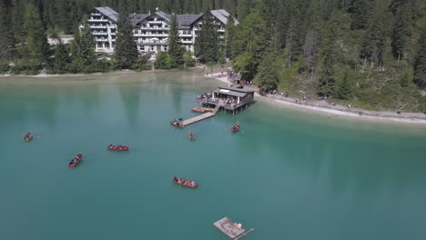 Paddle-boaters-in-Lake-Braies-aka-Pragser-Wildsee-in-South-Tyrol-Italy-with-the-Braies-Hotel-in-the-background,-Aerial-orbit-reveal-shot