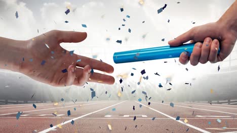 confetti falling over close up of a hand passing a baton against sports field