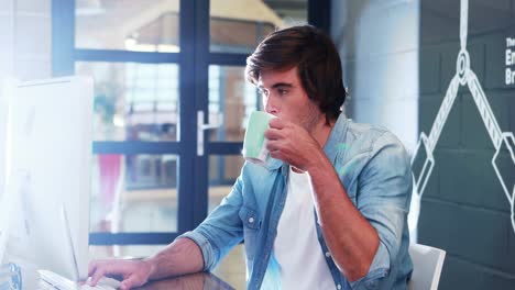 man having coffee while working on computer