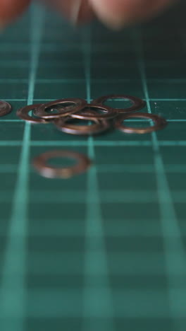 cu: professional designer takes silver eyelet details lying on green cutting mat with white lines extreme close view