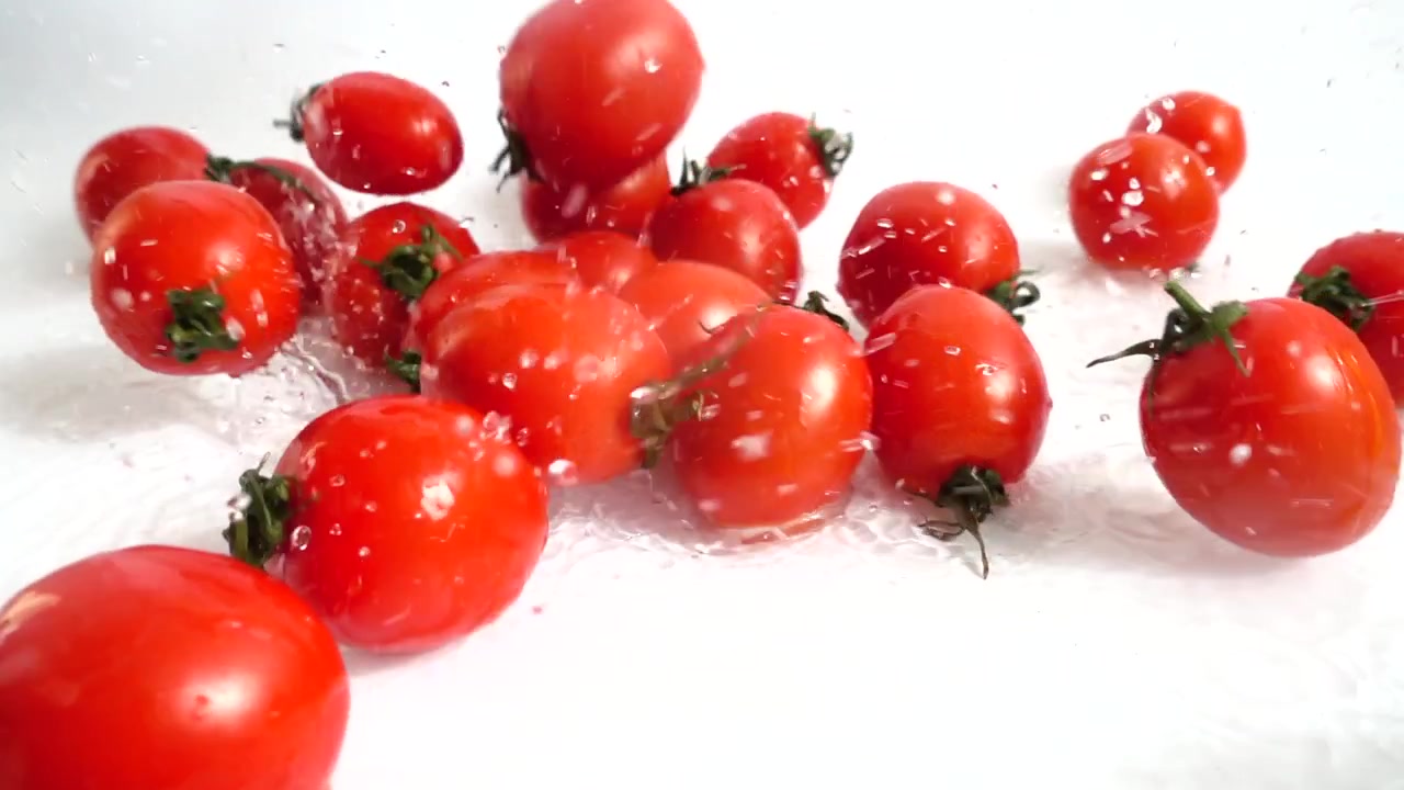 Kirschtomaten fallen ins Wasser. Zeitlupe