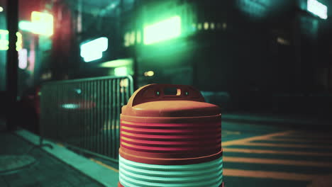 a lone barrier stands on a deserted city street at night, illuminated by neon lights.