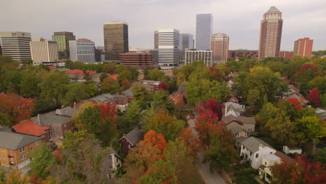 Aerial-flyover-beautiful-historic-Clayton-neighborhood-homes-with-downtown-city-skyline-on-the-horizon-in-the-Fall