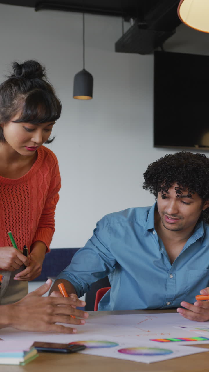 video vertical de personas de negocios bi-raciales felices discutiendo el trabajo durante una reunión en la oficina