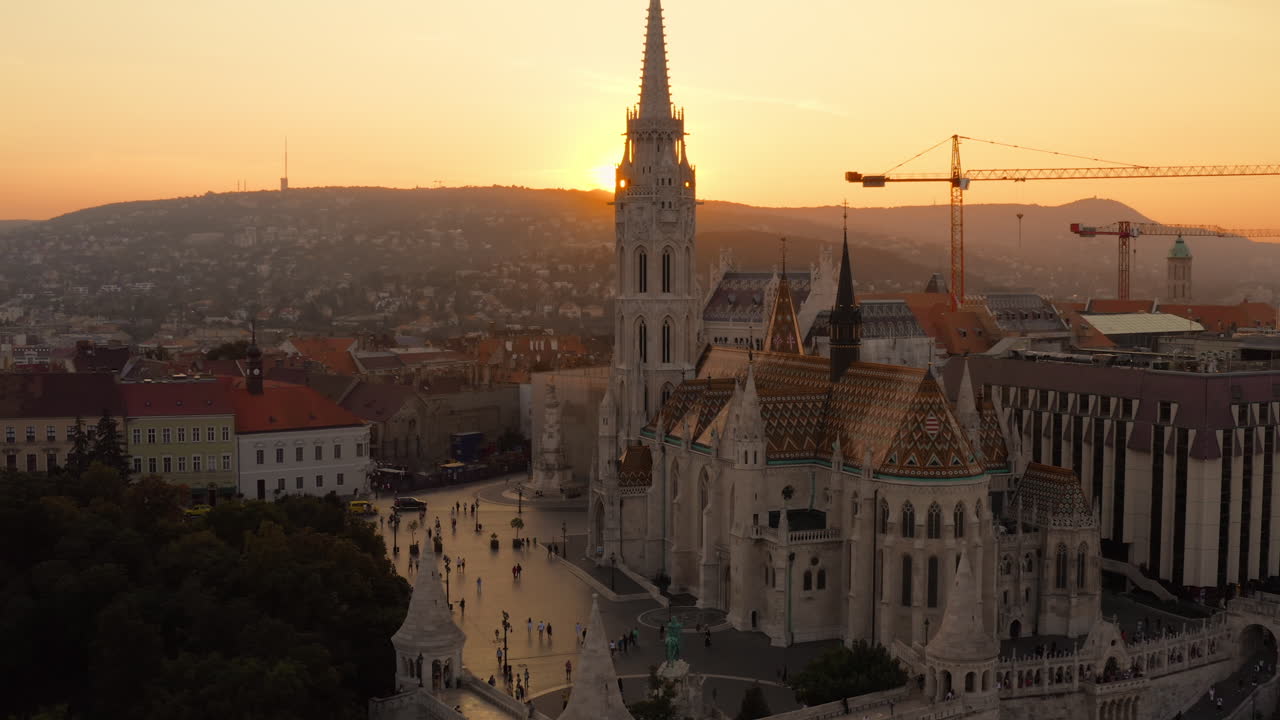Il sole tramonta dietro le colline di Buda, proiettando un bagliore illuminante sulla Chiesa di Mattia e dipingendo il cielo di arancione
