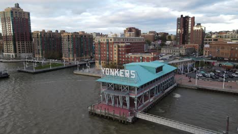 Drone-shot-from-river-flying-into-Yonkers,-New-York,-United-States,-on-a-partly-cloudy-day