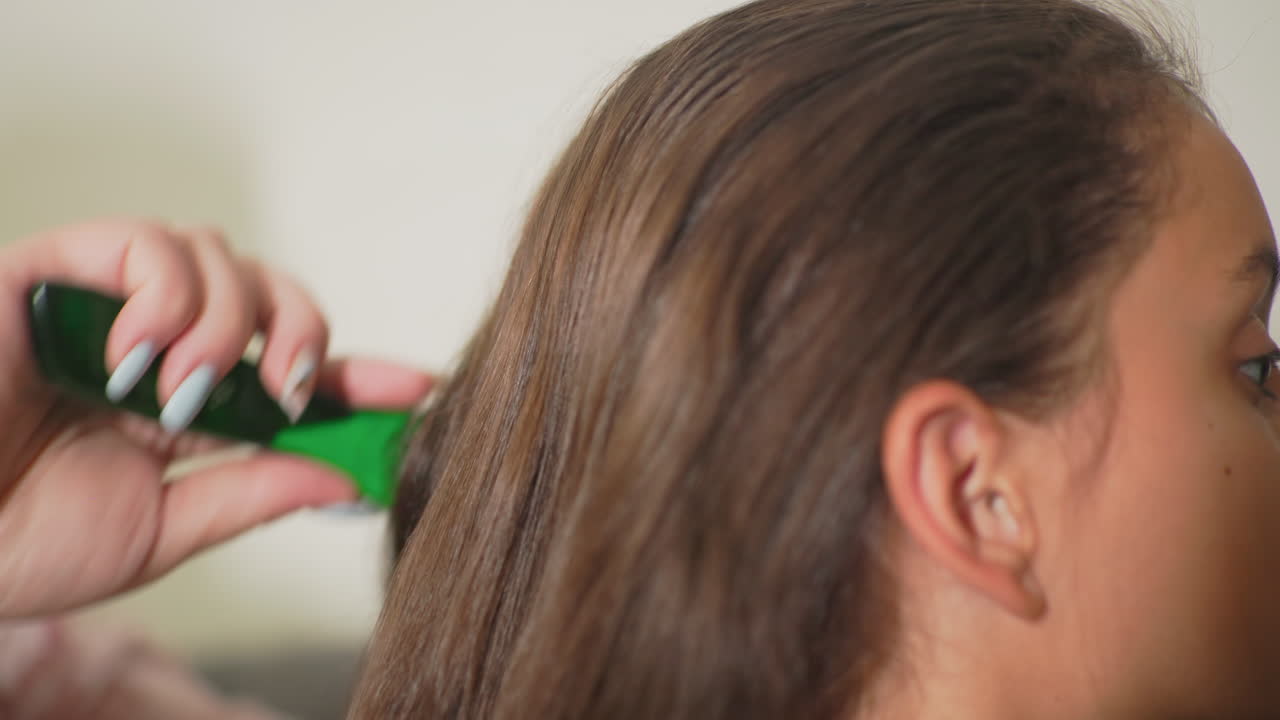 Close-up of hand gently holding daughter’s hair, brushing it with care. Intimate moment of affection and tenderness, showcasing connection and love, with soft natural light creating a warm atmosphere