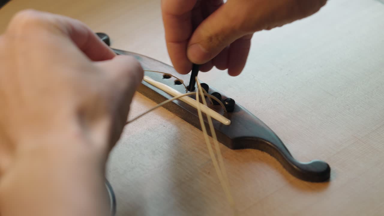 Luthier Installing New Strings And Pins Onto The Bridge Of An Acoustic Guitar