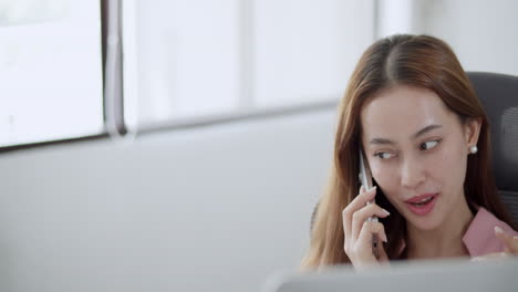 a businesswoman in a bright office is actively engaged in a phone call showcasing professionalism and focus.