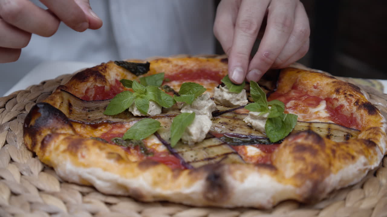 Chef puts basil leaves on top of neapolitan pizza