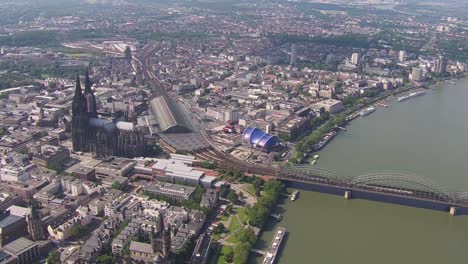 cologne cityscape with iconic cathedral and rhine river and a train entering, daytime, aerial view