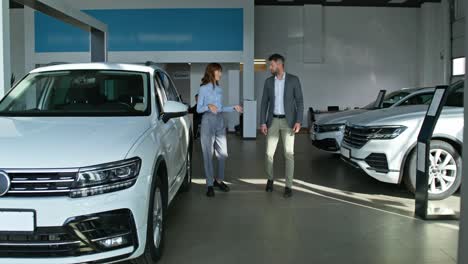 vendedor de coches discutiendo un coche con un cliente en una sala de exposiciones