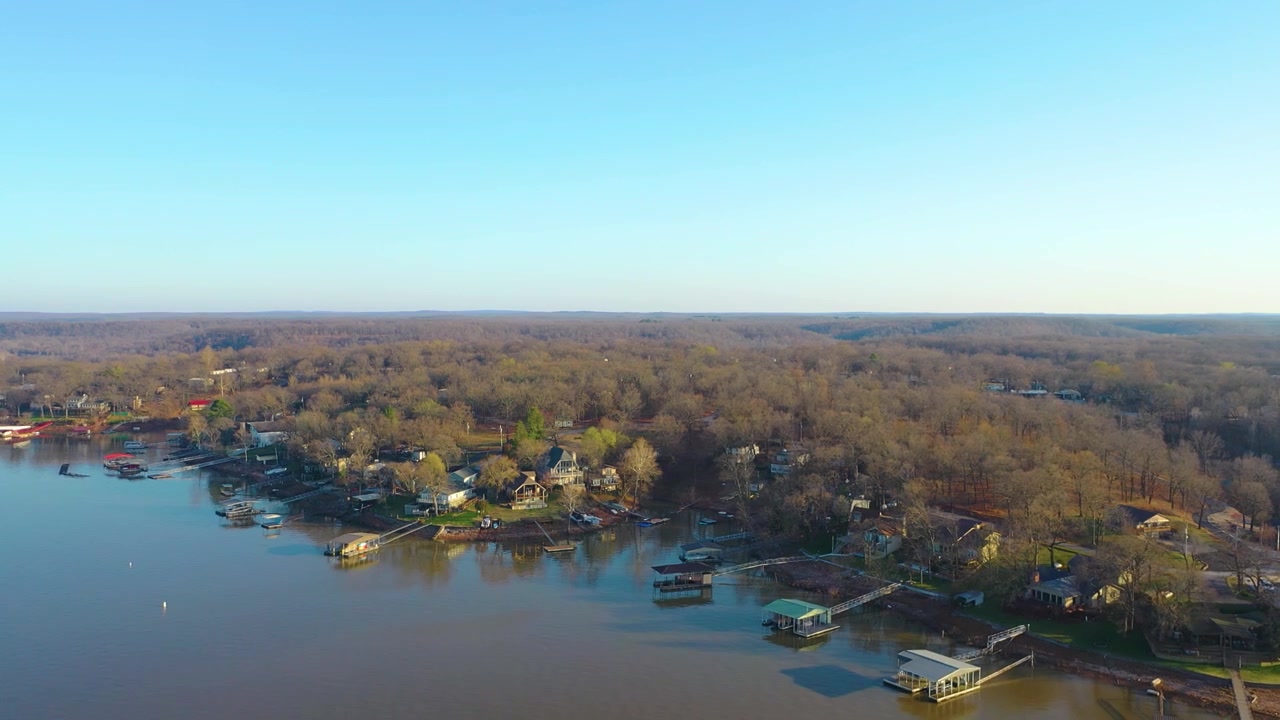 Cảnh quay drone dưới ánh nắng trên Hồ Table Rock, Missouri, với mặt nước hồ chứa yên tĩnh, những ngôi nhà ven hồ, bến thuyền có mái che và bờ hồ rợp cây trong một khu dân cư thanh bình ở Ozarks
