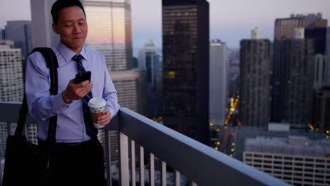 asian businessman using technology on rooftop at sunrise