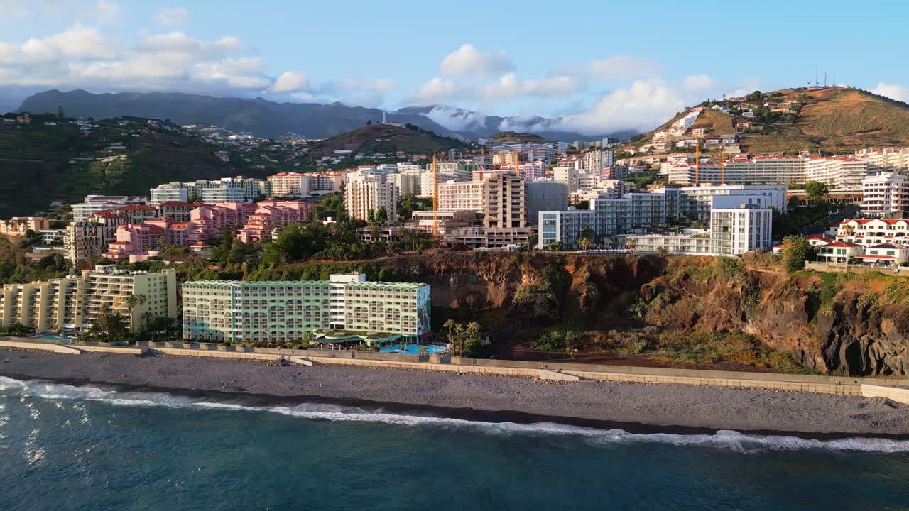 Vista aérea de la Praia Formosa en Funchal, Madeira, que muestra acantilados, resorts, costa y olas del océano. Ideal para viajes, turismo, destinos europeos y temas de paisajes costeros.