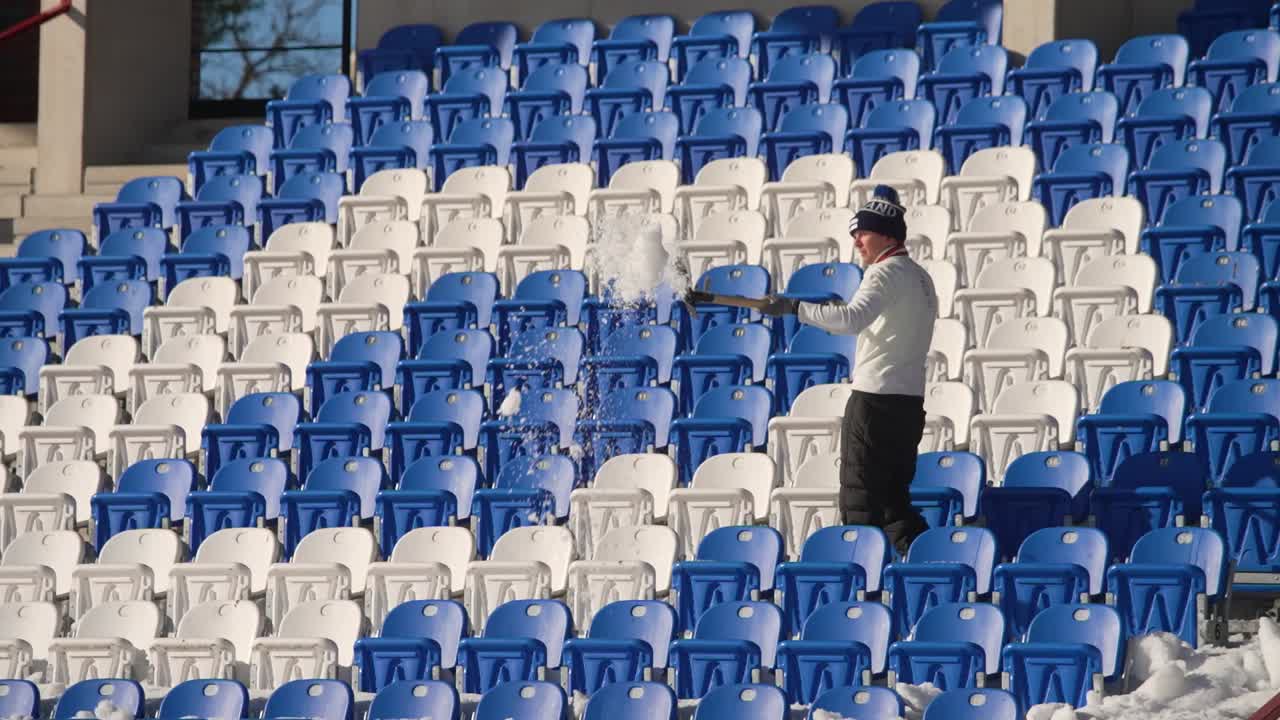 toma distante de un hombre tirando nieve con una pala en un estadio de esquí