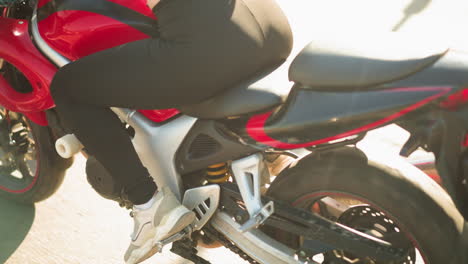 back view of a moving motorcycle with a close-up of the wheel and a rider s leg in canvas shoes on the footrest, rides from a sunny place to a shady place