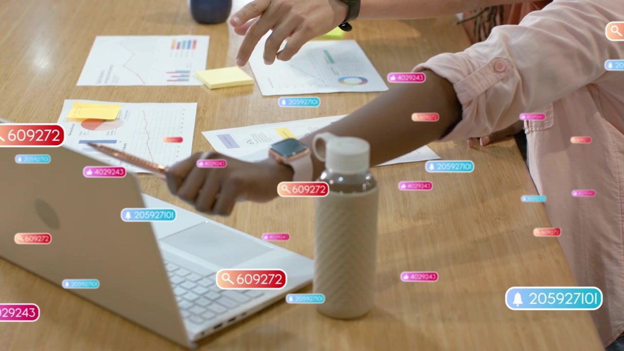 Right woman gripping pen, tapping trackpad and causing floating data icons during business review