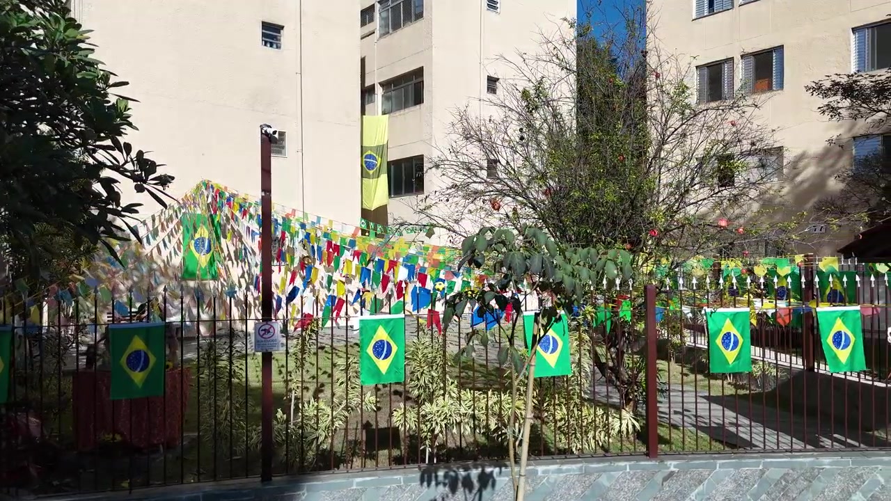 Lateral drone tracking shot showcasing a beautiful building decorated with Brazilian flags during the 2026 FIFA World Cup.