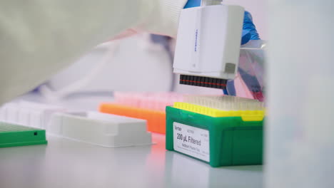 primer plano de científico en guantes azules recargando puntas en pipeta multicanal en laboratorio de investigación, 4k