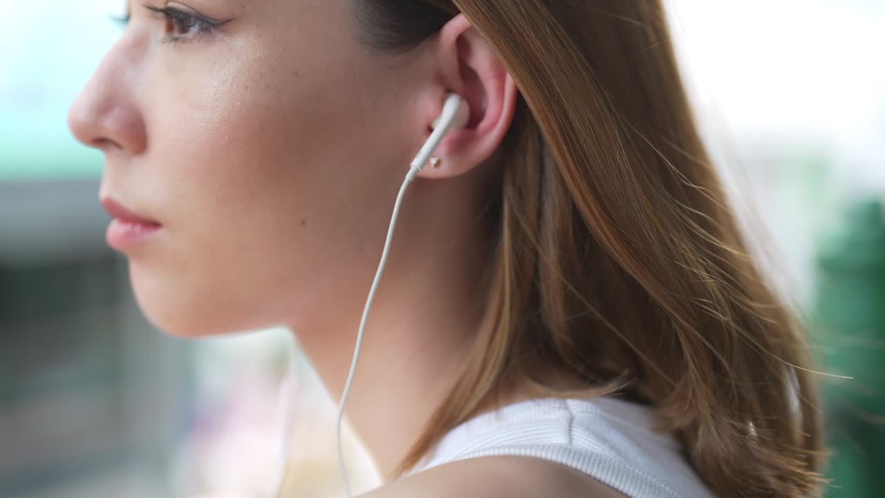 retrato en 4k de una joven asiática caminando por la calle de la ciudad escuchando música de los auriculares