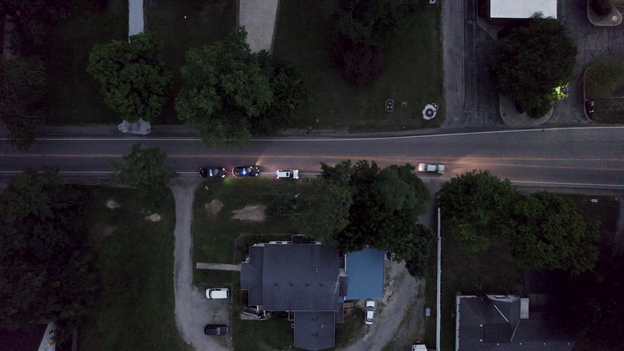 An aerial shot of a cop car pulls over a speeding driver on the main road in the evening time