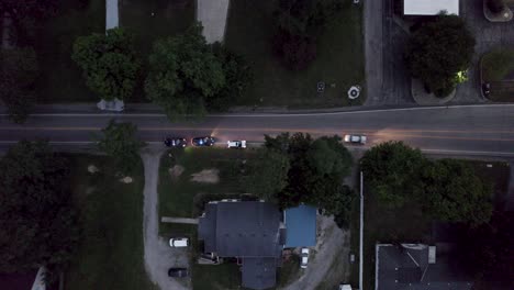 an aerial shot of a cop car pulls over a speeding driver on the main road in the evening time