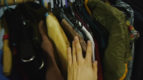 person looking through clothes in a closet.