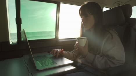 mujer viajera trabajando en una computadora portátil en una furgoneta