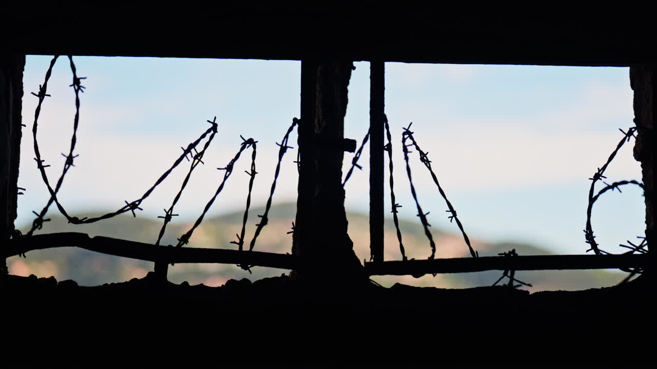 Close up of barbed wire loops along a small window