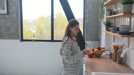mujer bebiendo agua en una cocina moderna