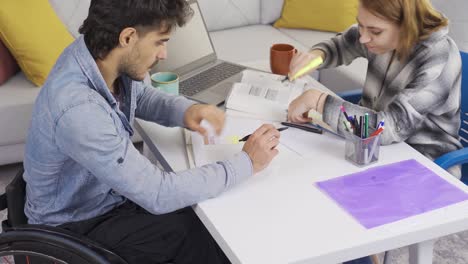 un estudiante discapacitado y su novia estudian juntos en casa. usando una silla de ruedas.